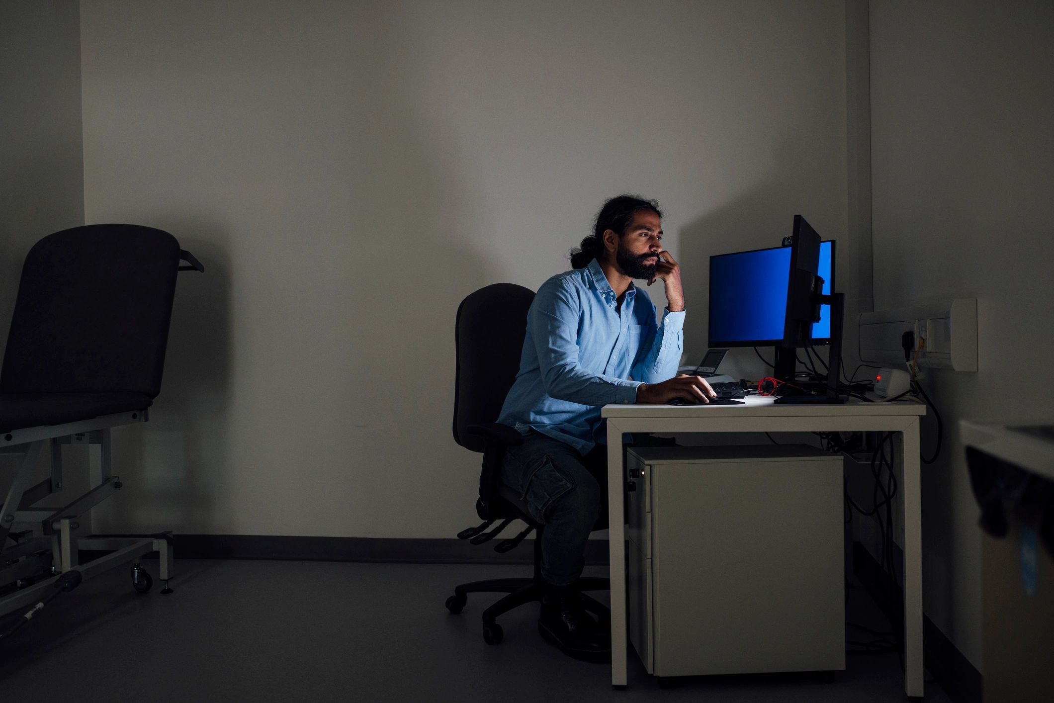Researcher working late at a computer workstation in a dark studio